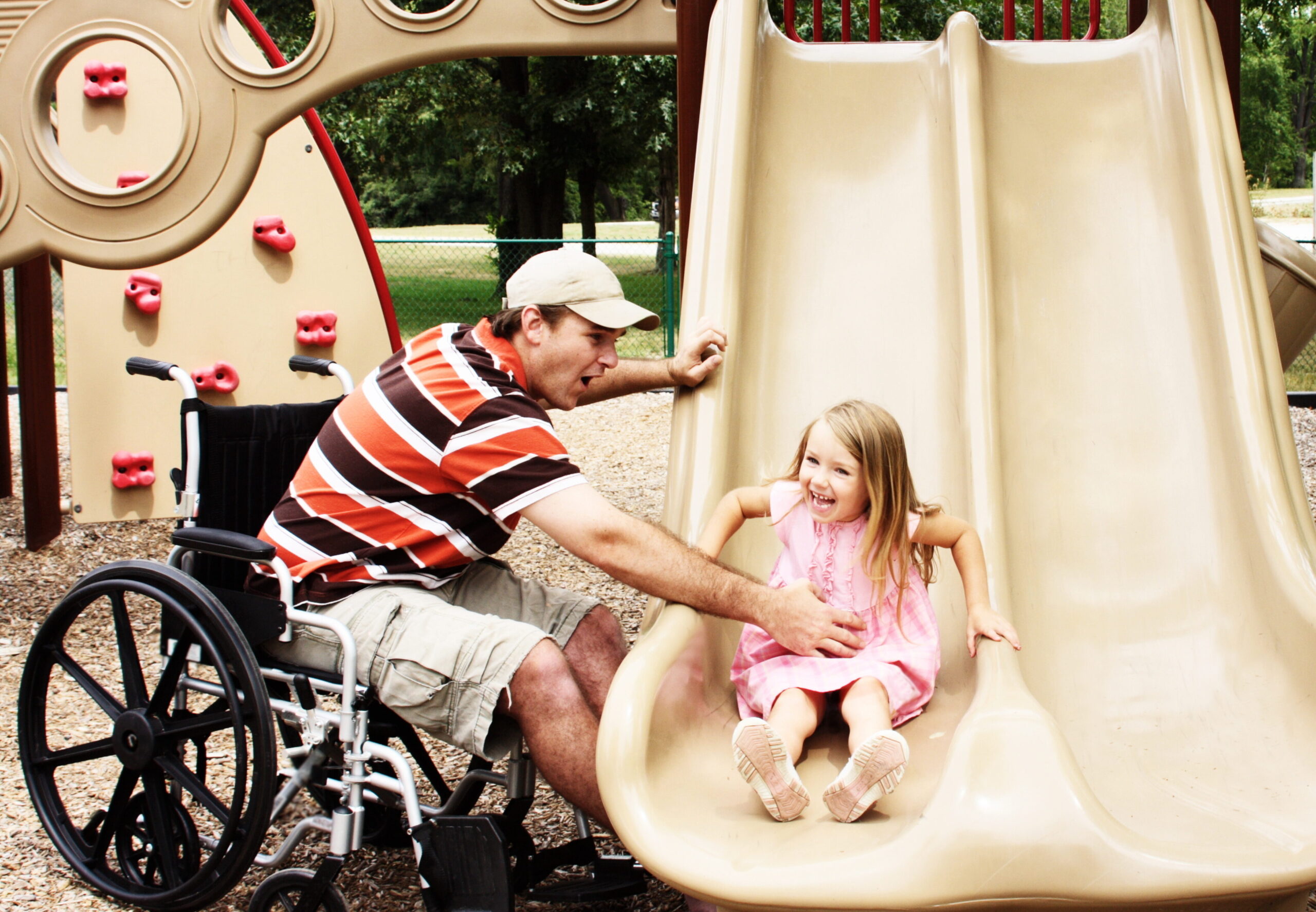 Man in wheelchair playing with his daughter at the park